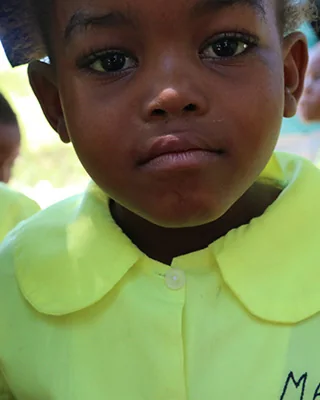 A kindergarten student in a green uniform